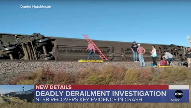 Amtrak Train Derailed in Montana. The train car is fully on its side as workers mill around on the track. A red ladder leans against the train car