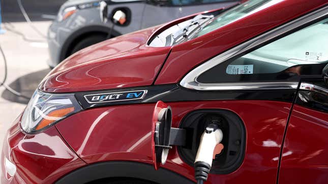 Close-up on a red Chevrolet Bolt EV's charging port as it is plugged in and recharging.